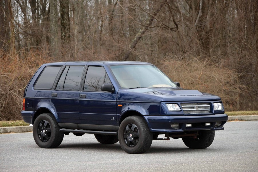 A dark-blue 1998 Laforza Magnum Edition in a parking lot by a forest