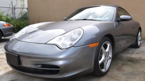 The front 3/4 view of a gray 2002 Porsche 911 Carrera in a parking lot