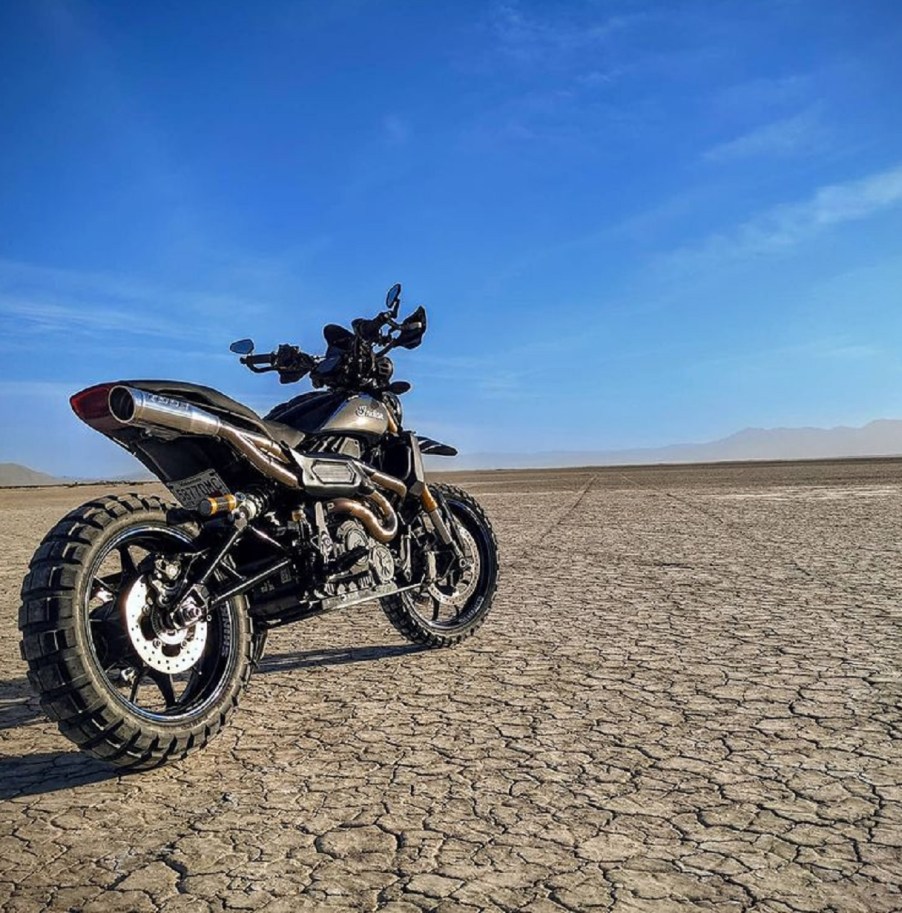 The rear 3/4 view of Trail Tech's gray 2019 Indian FTR 1200 S Adventure Custom in the desert