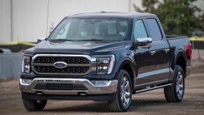 A dark colored 2021 Ford F-150 parked in front of a white building.