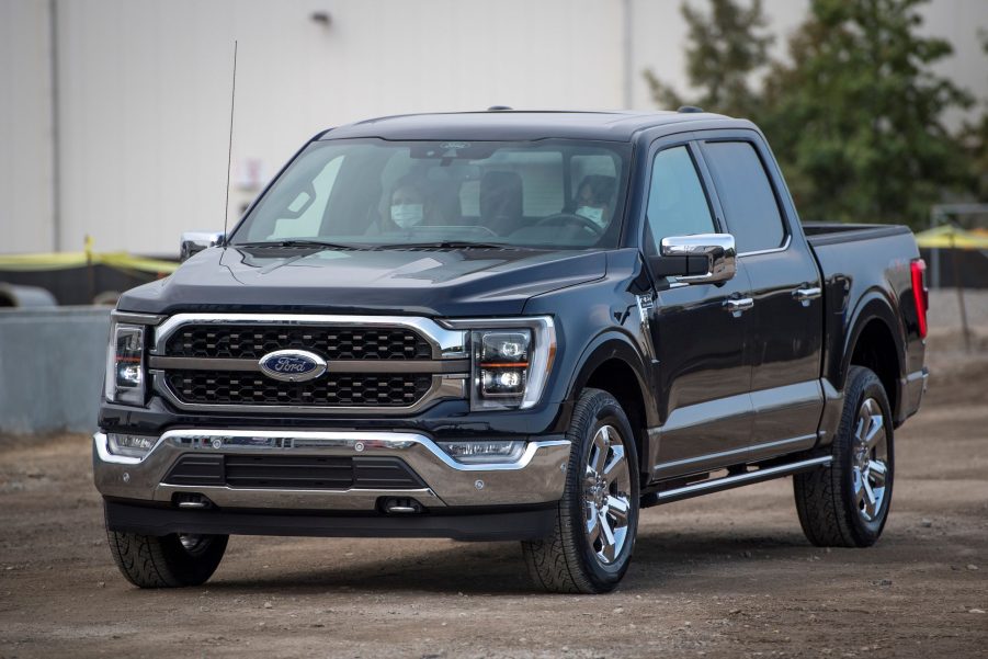 A dark colored 2021 Ford F-150 parked in front of a white building.