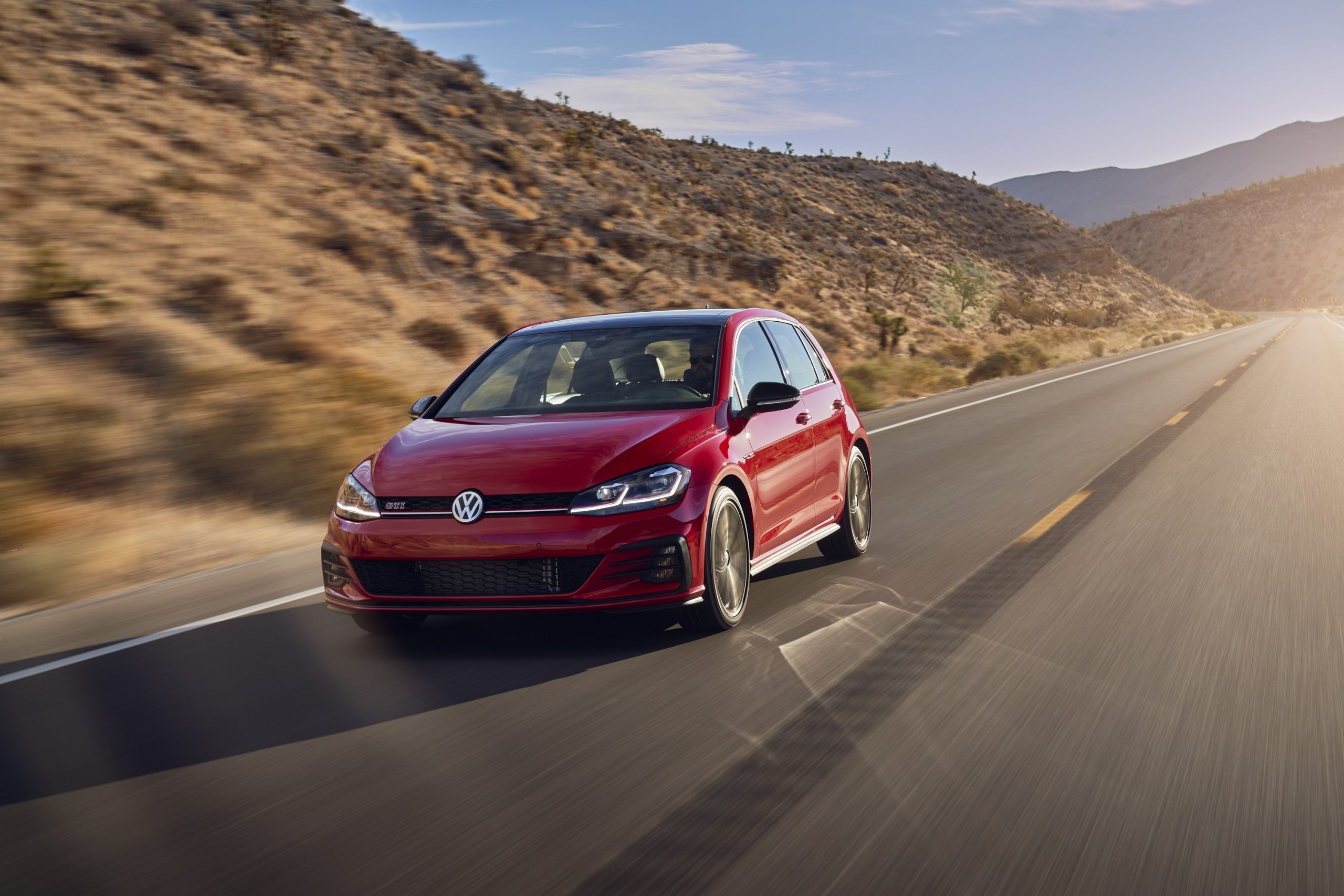 A red Volkswagen GTI shot from the front 3/4 on a back road