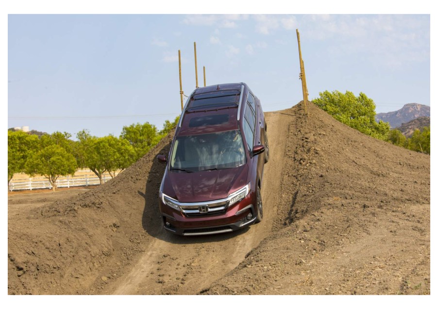 A maroon 2022 Honda Pilot drives off-road in the dirt, it's more expensive for the new model year.