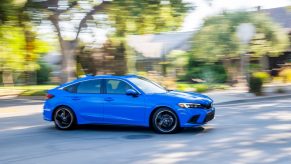 A blue 2022 Honda Civic hatchback shot in profile on a shaded street