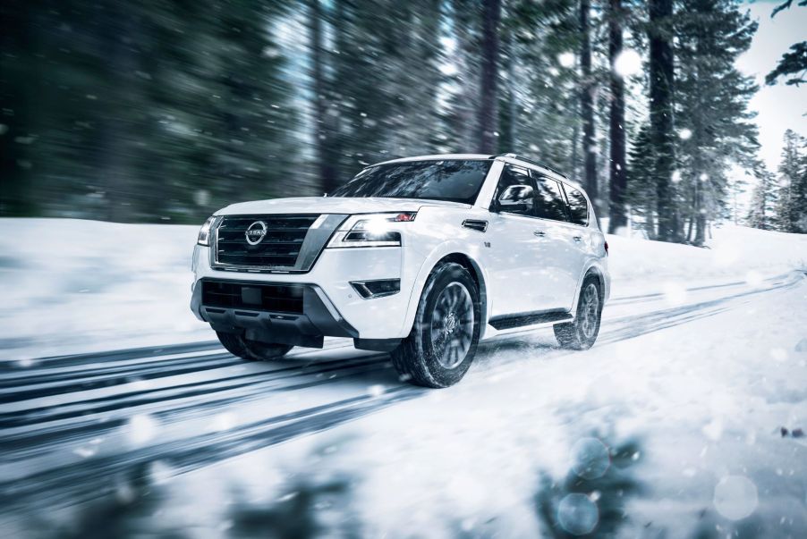 The 2022 Nissan Armada full-size SUV in white driving on a forest road during the winter