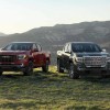 Four GMC pickup trucks parked in front of mountains.