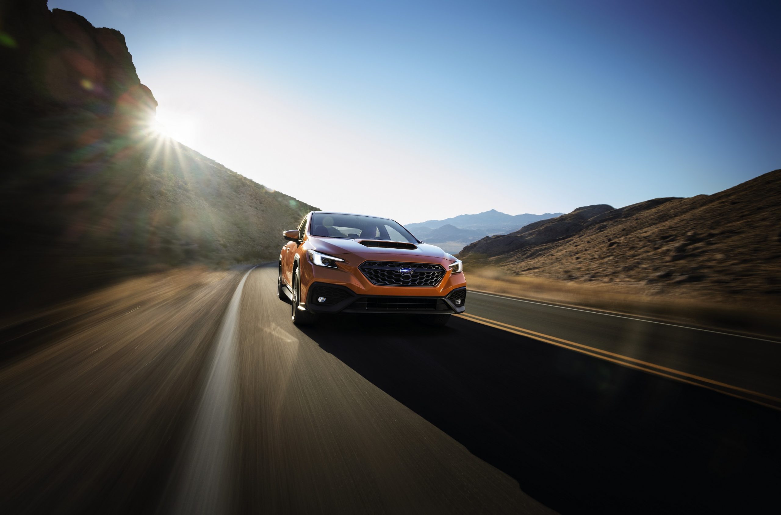 An orange 2022 Subaru WRX shot on a canyon road