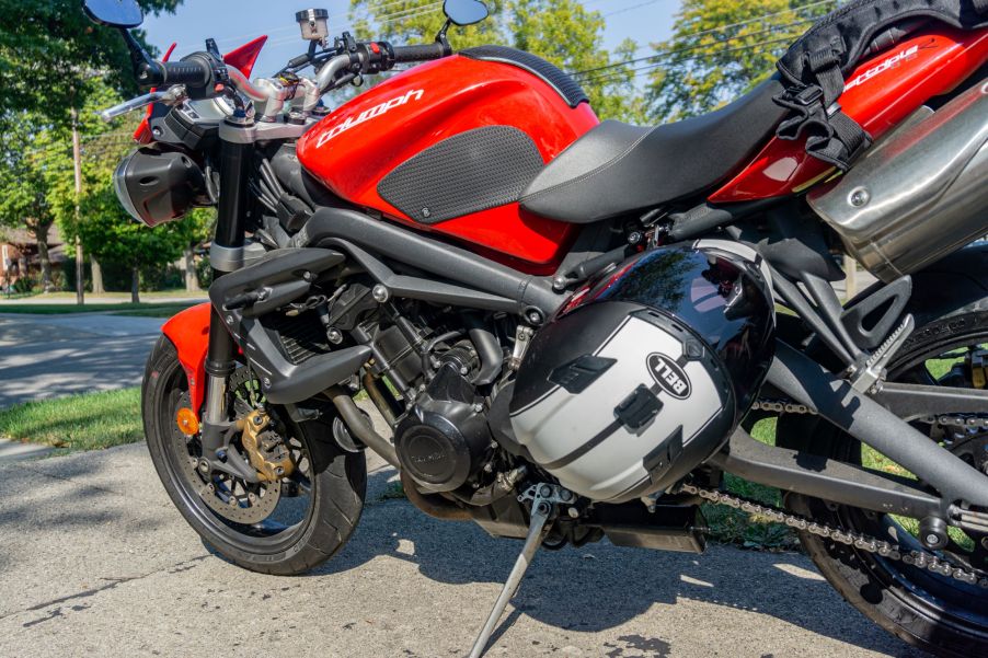 A black-and-white Bell motorcycle helmet locked to a red 2012 Triumph Street Triple R with a Kuryakyn lock