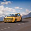 A yellow Lancia Delta Integrale drives through the French Alps