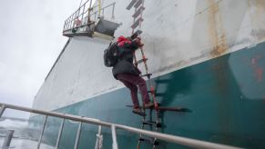 A boat with a ladder and person climbing up it.