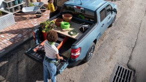 A woman standing by the bed of a blue 2022 Ford Maverick compact pickup truck