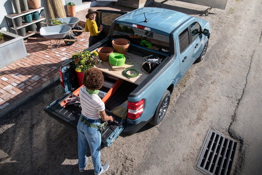 A woman standing by the bed of a blue 2022 Ford Maverick compact pickup truck