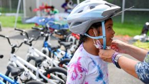 An adult helps a child adjust their bicycle helmet