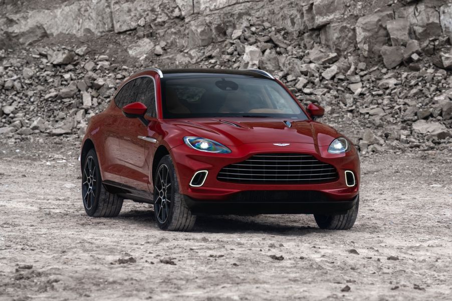 A red Aston Martin DBX in a rocky area on dirt.