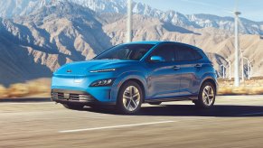 Blue 2022 Hyundai Kona Electric driving by windmills