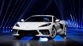 A white C8 Corvette Stingray in front of a black background with blue lights.