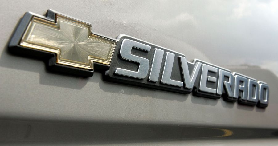 A Chevy Silverado logo on a beige colored truck.