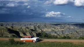 Classic Car Driving Down Dirt Road On Road Trip