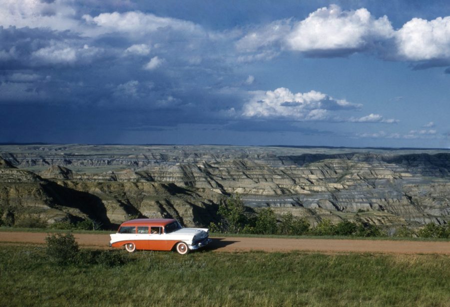 Classic Car Driving Down Dirt Road On Road Trip