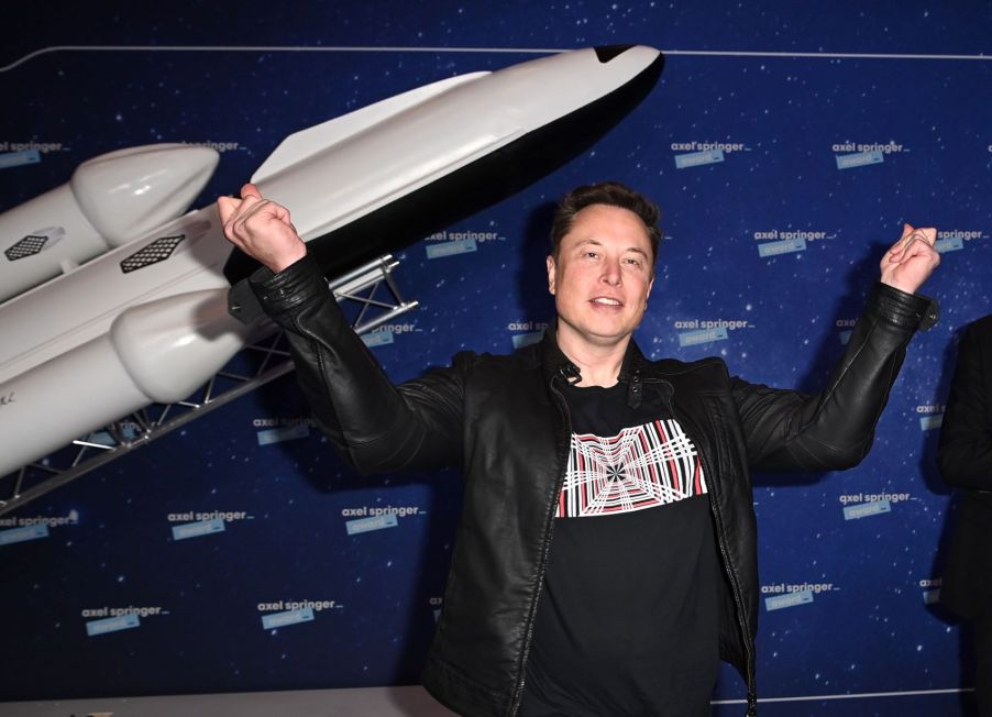 Elon Musk standing in front of a model of a rocket