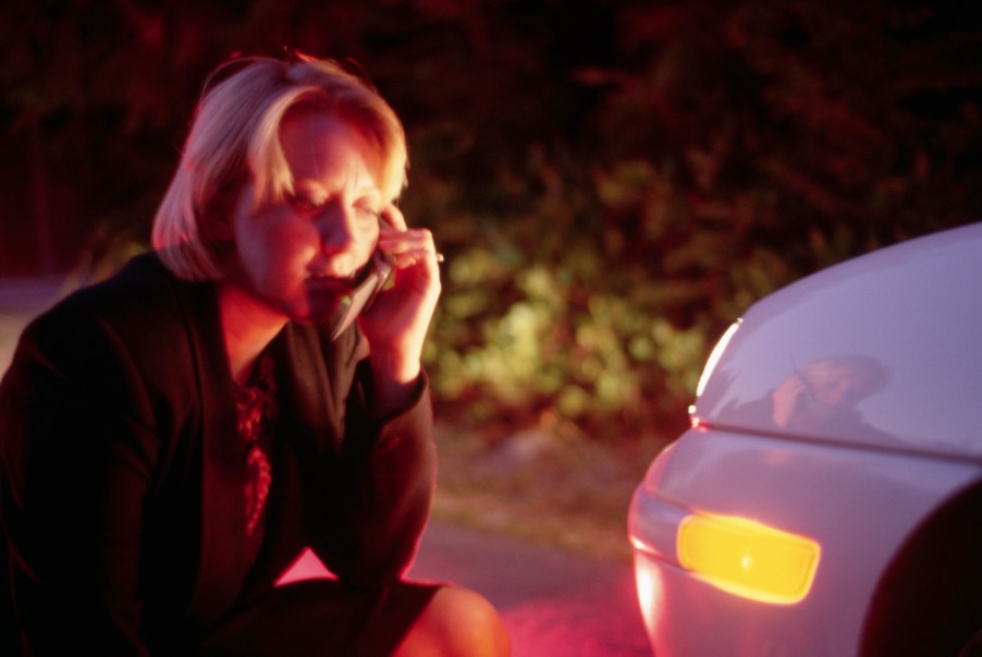 This is a photo of a woman examining the front of her sedan and calling for help. 466,000 Sonata sedans are at risk of a turn signal malfunction and affected by Hyundai recall. Doug Wilson/CORBIS/Corbis via Getty Images