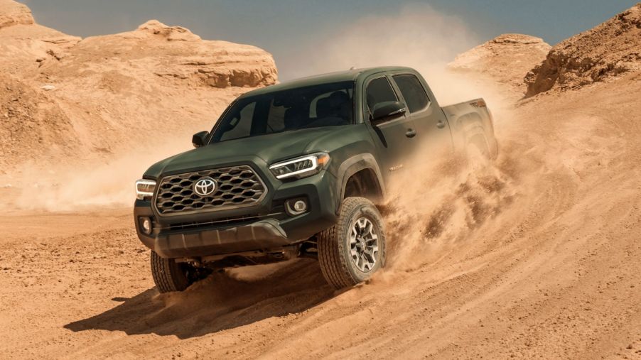 Green 2022 Toyota Tacoma driving down a sandy hill