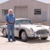 Jay Leno with a silver 1964 Aston Martin DB5 Goldfinger Continuation in a parking lot