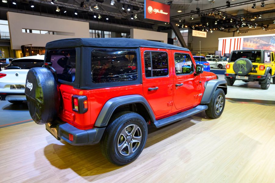 The back of a red Jeep Wrangler with a black top.