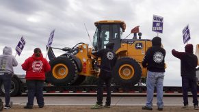 A truck hauls a piece of John Deere equipment from the factory past workers picketing outside of the John Deere. John Deere Strike: Workers Strike Over Contract. A truck hauls a piece of John Deere equipment from the factory past workers picketing outside of the John Deere