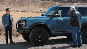 Kevin Bacon and Jay Leno standing next to a blue 2021 Ford Bronco Sasquatch