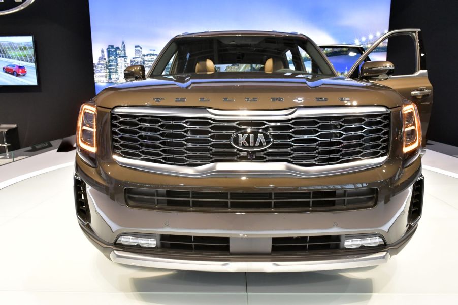 A gold Kia Telluride on a white platform in front of a blue background.