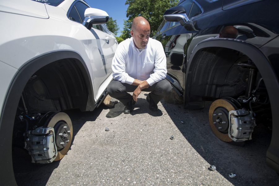 a man staring at two car at a dealership with missing wheels. Is the TikTok "lug nut challenge" real or just halloween hysteria?