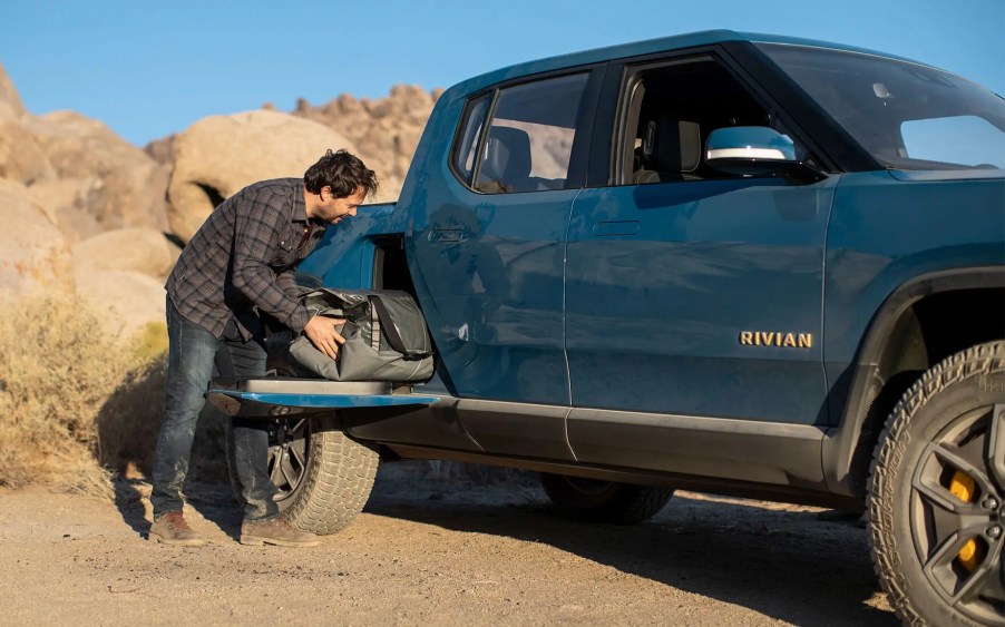 Man placing a bag in the gear tunnel of a blue Rivian R1T