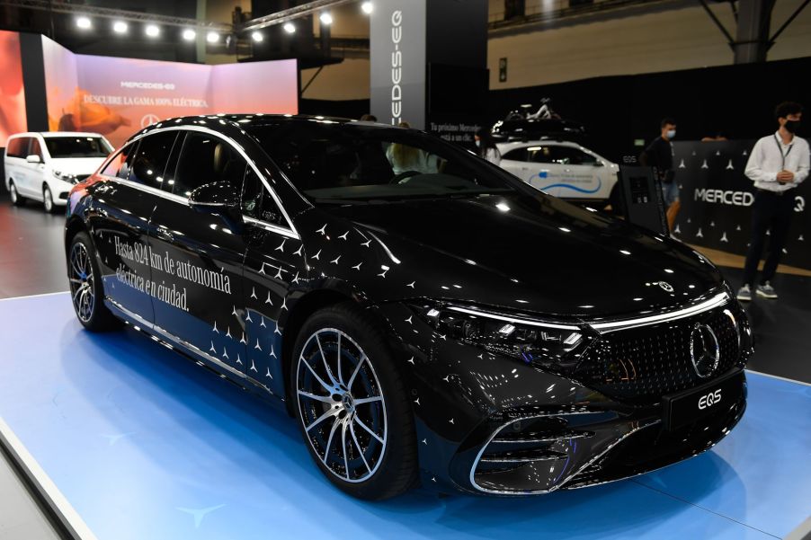 A black Mercedes EQS on a blue pad inside a building.