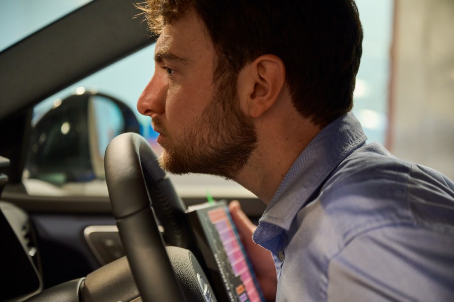 The 'Nose of Nissan,' Peter Karl Eastland, sniffs a steering wheel in a Nissan car