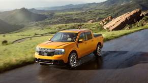 Orange 2022 Ford Maverick compact pickup truck driving on a mountainous road, its newly announced fuel economy rating is superb.