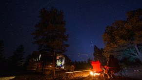 A sprinter van camps outside by a fire