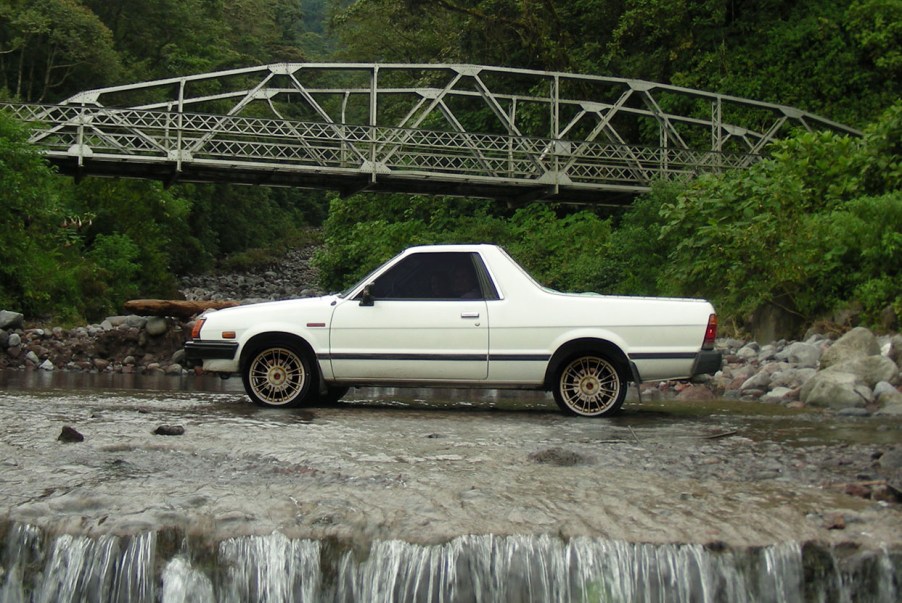 A white Subaru Brat parked near a bridge