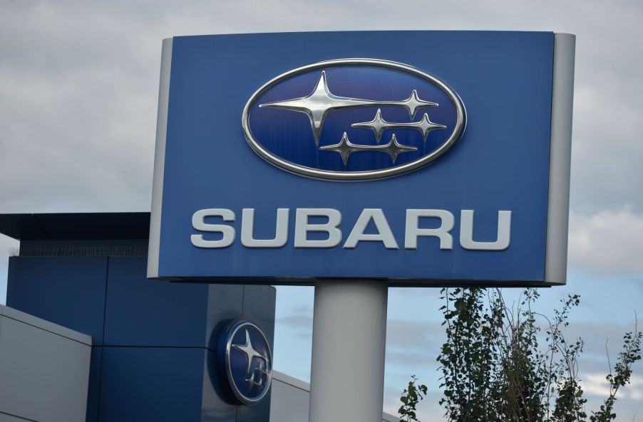 Subaru sign with the logo and name written on it in front of a cloudy background.