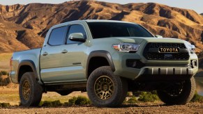 A moss green Toyota Tacoma in a desert.