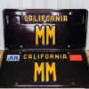 Two black and yellow California vanity license plates with the letters "MM"