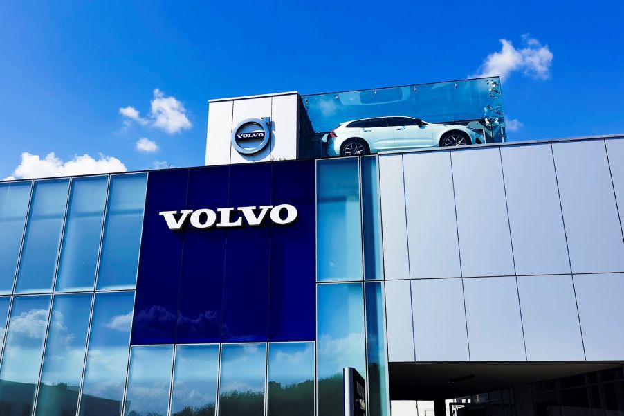 A Volvo building with a car displayed on top and the name written on the sign over many windows.