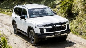 White 2022 Toyota Land Cruiser driving on a muddy road