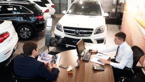 Car salesperson at a desk talking to customers