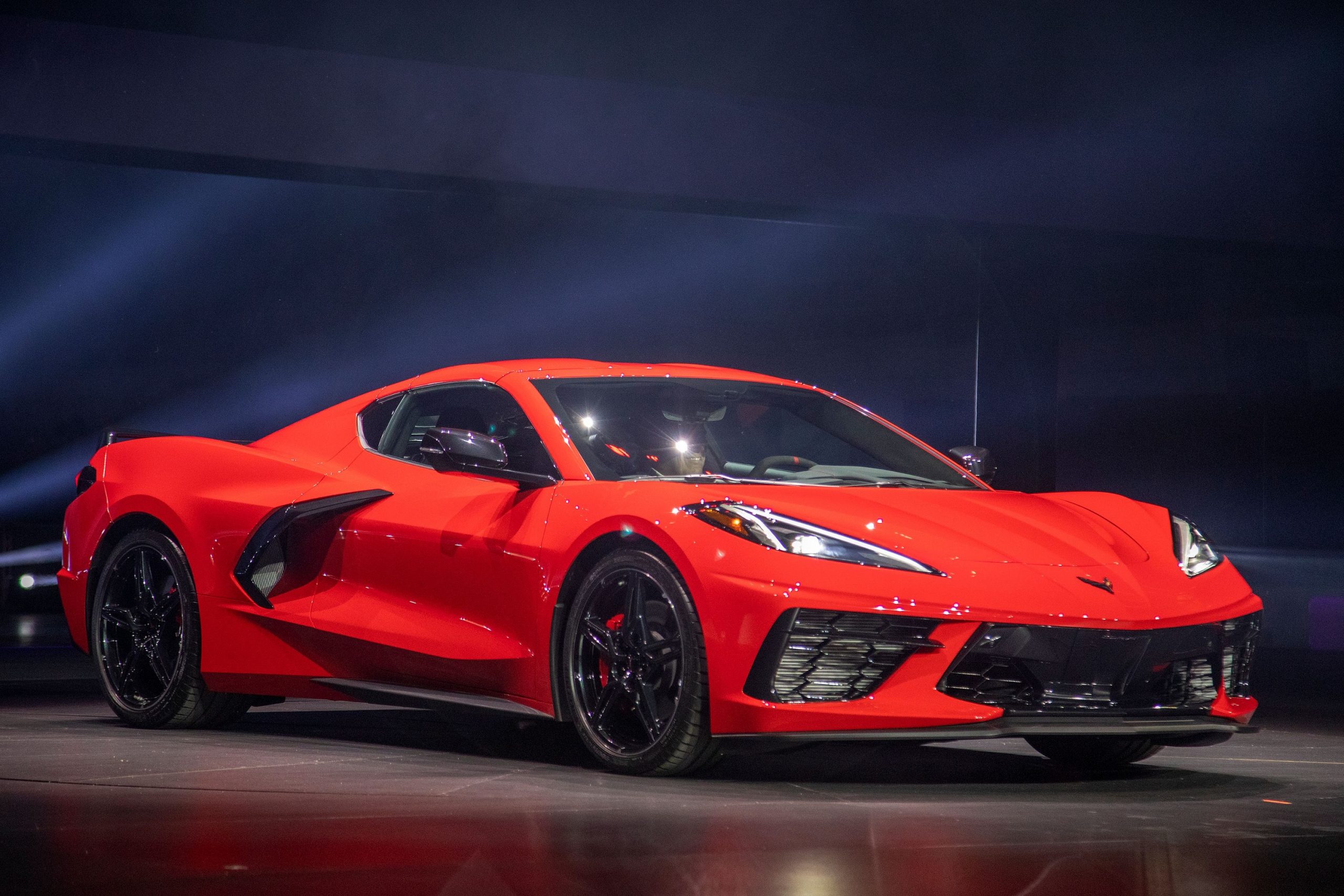 A red Chevrolet Corvette on stage at an auto show, shot from the 3/4 angle