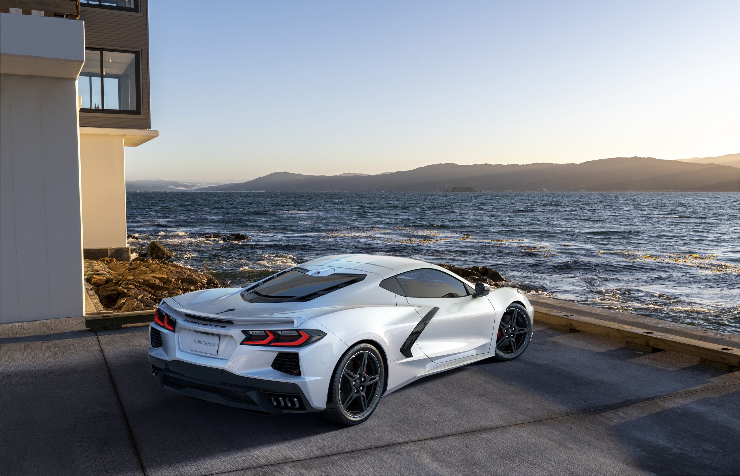 A white Chevrolet Corvette shot from the rear facing the sea