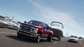 A red 2021 Ford F-450 towing a boat down the highway.