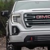 A white 2022 GMC Sierra 1500 AT4 driving through woods.