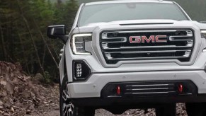 A white 2022 GMC Sierra 1500 AT4 driving through woods.