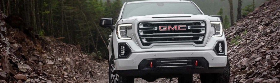 A white 2022 GMC Sierra 1500 AT4 driving through woods.